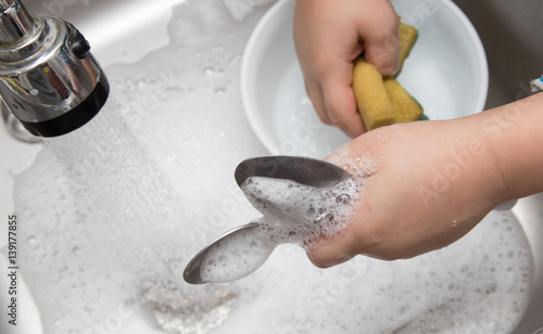 Fotografie boy washing dishes in the kitchen