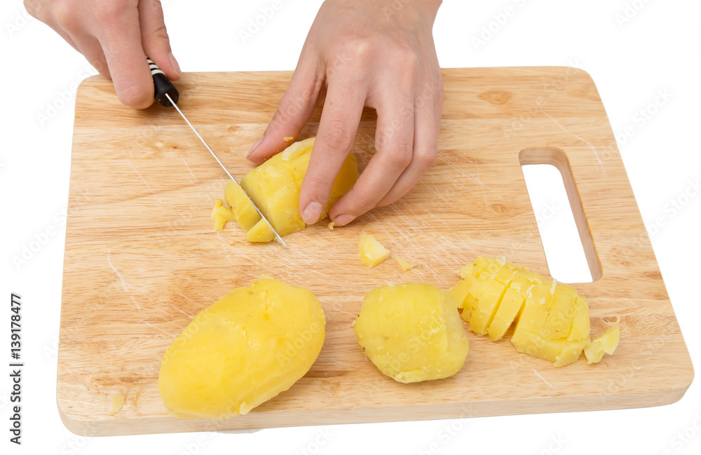 Chef cuts boiled potatoes on board on a white background Chef cuts boiled potatoes on board on a white background