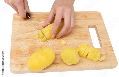 Chef cuts boiled potatoes on board on a white background