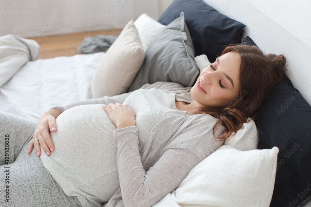 Pregnant smiling female lying on bed Pregnant smiling female lying on bed