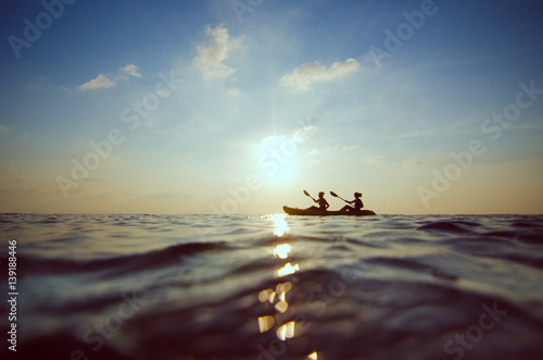 silhouette of people kayaking at sunset