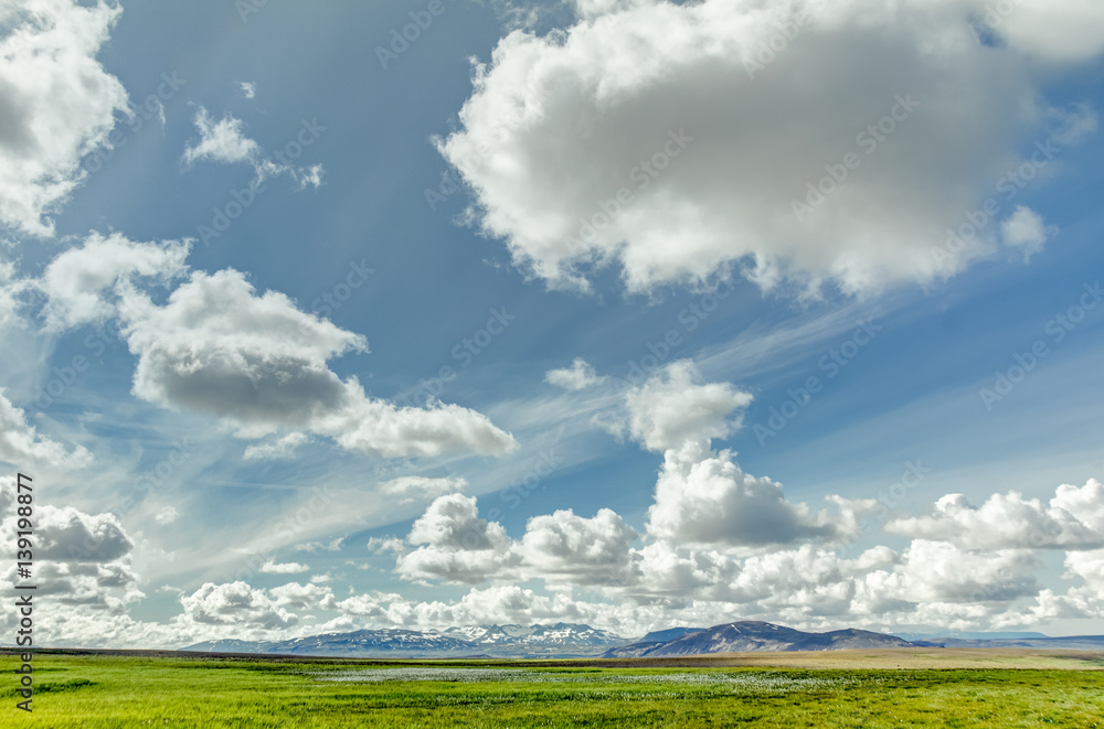 Open grassland with cloudscape and mountains in background. Iceland. Open grassland with cloudscape and mountains in background. Iceland.