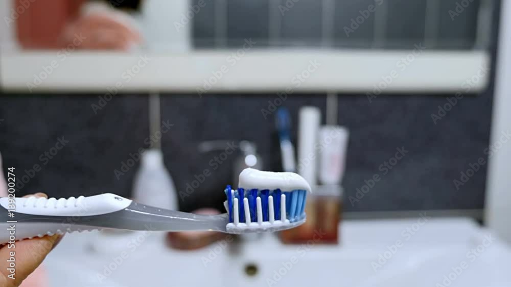 The woman squeezed toothpaste on the toothbrush in the bathroom. The woman squeezed toothpaste on the toothbrush in the bathroom.