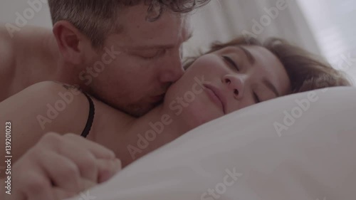 Beautiful passionate couple having sex on bed. Intimate young couple during sensual foreplay in bed.