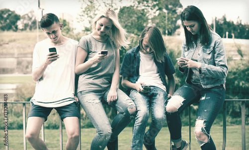 Teenagers with phones in park.