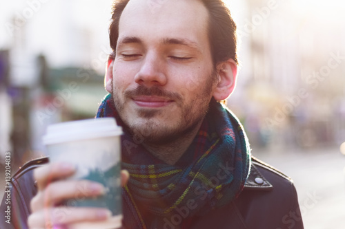 Valokuva Scarfed man enjoying warm beverage on a sunny winter day