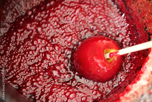 Foto Red tasty caramelized apple in a copper pot with syrup