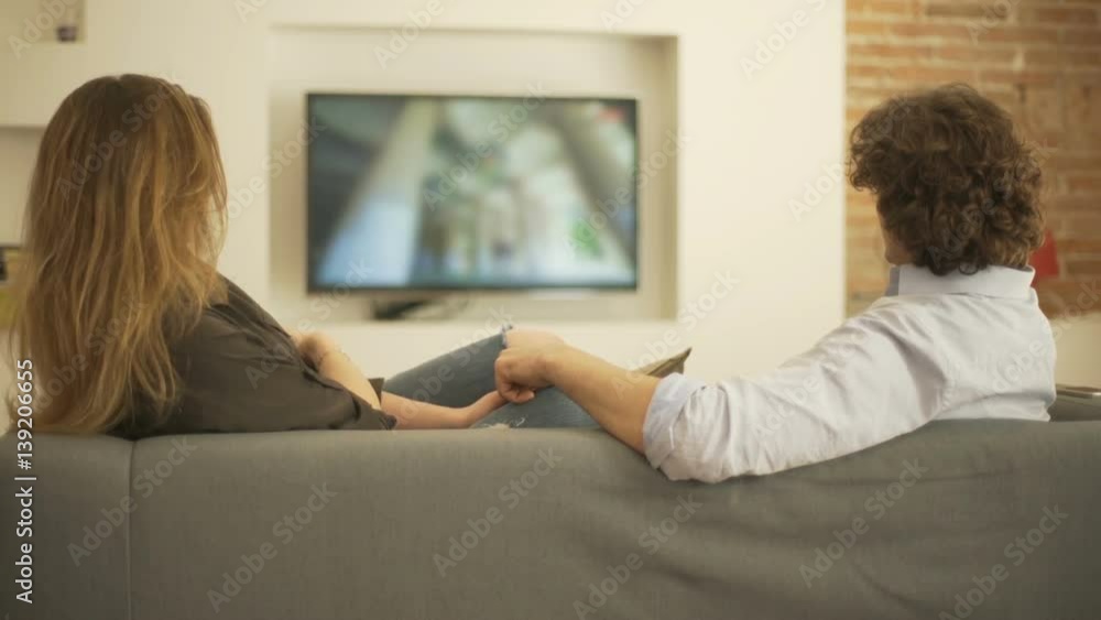 Couple sitting on the sofa and watching something on television
Couple sitting on the sofa and watching something on television