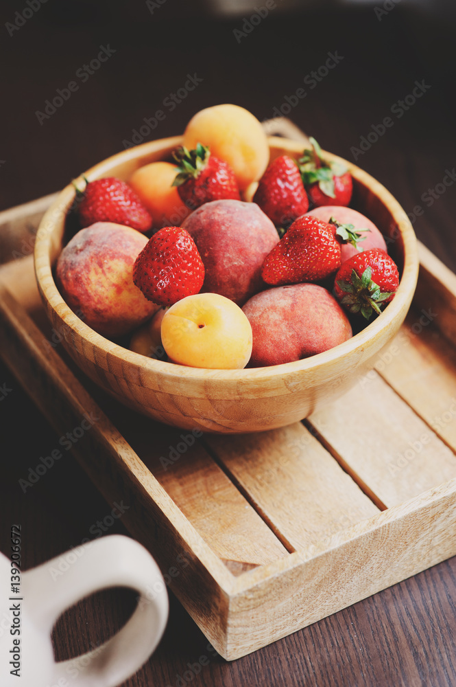 fresh summer fruits on wooden plate. Strawberries, peaches and apricots in rustic farm kitchen fresh summer fruits on wooden plate. Strawberries, peaches and apricots in rustic farm kitchen