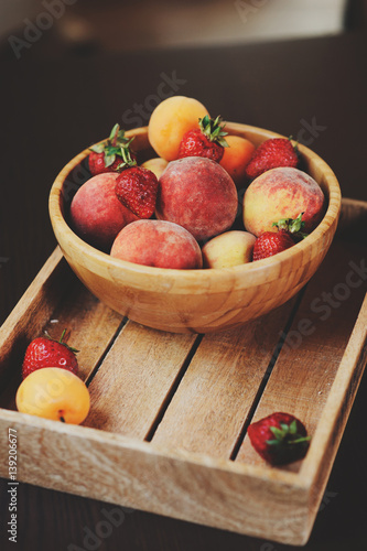 fresh summer fruits on wooden plate. Strawberries  peaches and apricots in rustic farm kitchen