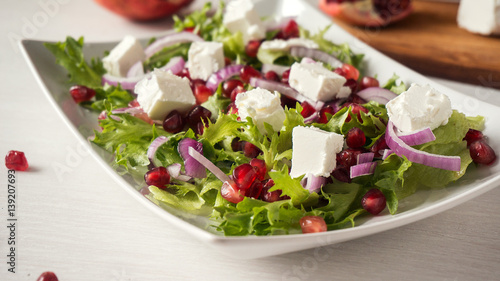 Healthy salad with pomegranate seeds, feta cheese and red onion.