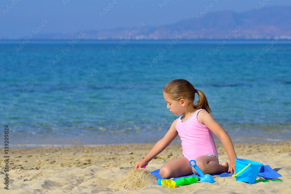 Adorable toddler girl playing with her toys at beach Adorable toddler girl playing with her toys at beach