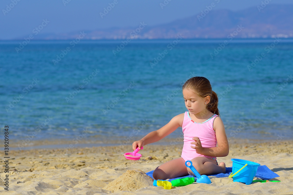 Adorable toddler girl playing with her toys at beach Adorable toddler girl playing with her toys at beach