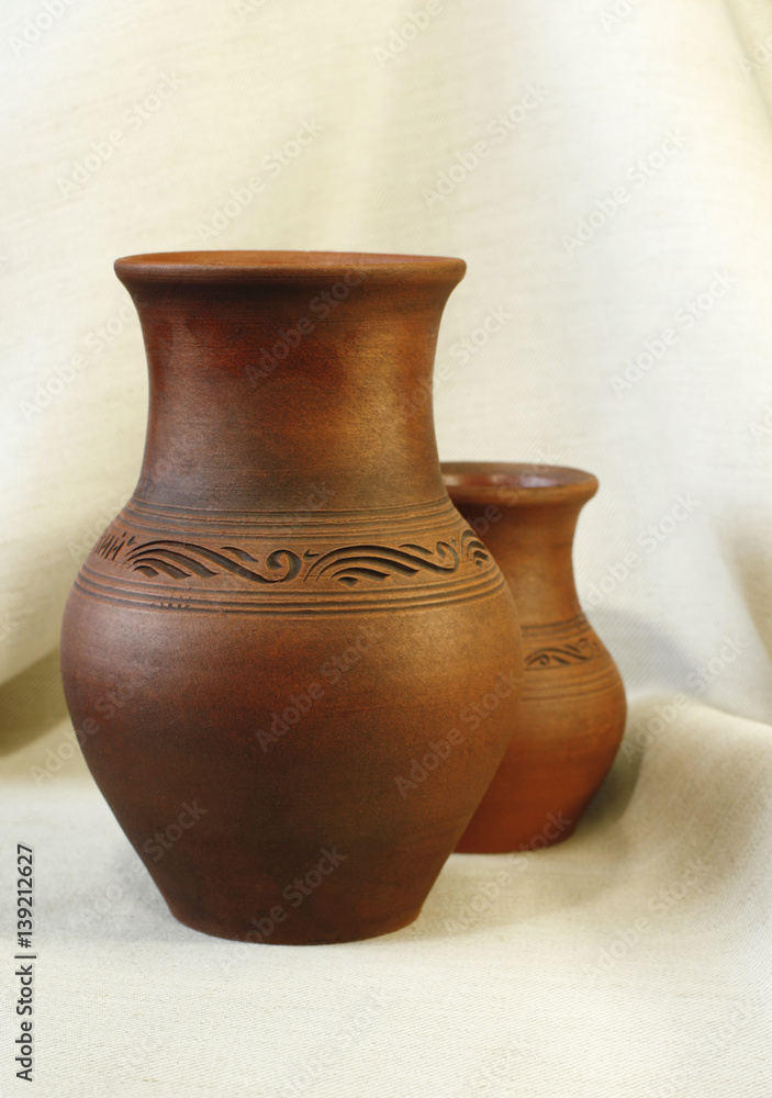 Two clay pots on the background of linen cloth with pleats close up Two clay pots on the background of linen cloth with pleats close up