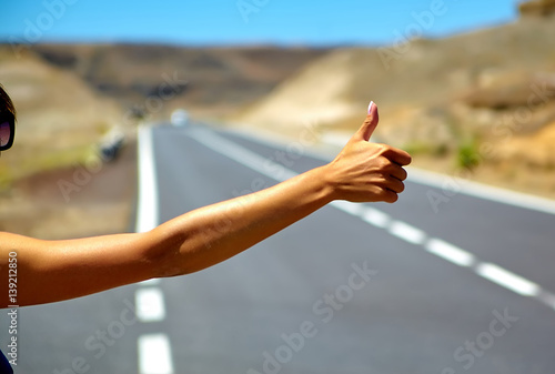 Принти на полотні Young caucasian tourist hitchhiking along a road in sunset