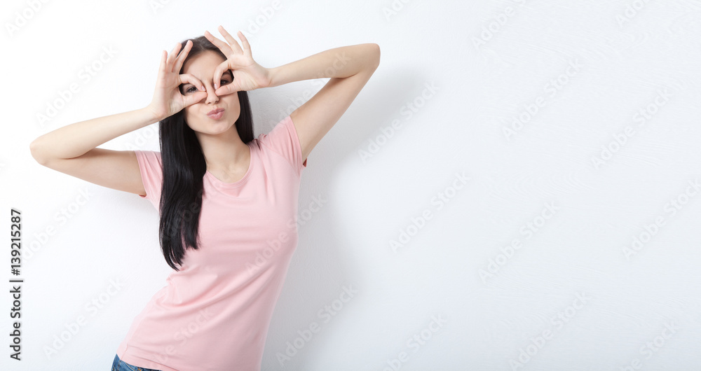 Look here. Attractive young woman looking through binoculars to see the world. Portrait of happy girl your hands up on white. Look here. Attractive young woman looking through binoculars to see the world. Portrait of happy girl your hands up on white.