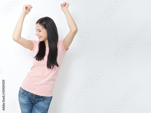 Look here. Attractive young woman relax and dance on copy space. Portrait of happy girl dancing your hands up on white background