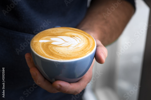 dark blue cup of coffee with art design made hot milk hand phone table
