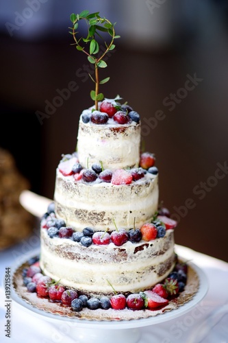Delicious chocolate wedding cake decorated with fruits and berries