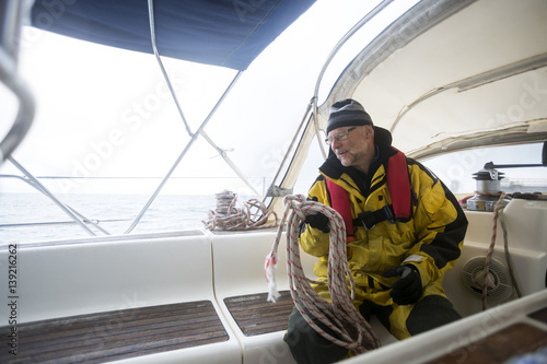 Man Holding Rope While Sitting On Yacht © Tyler Olson