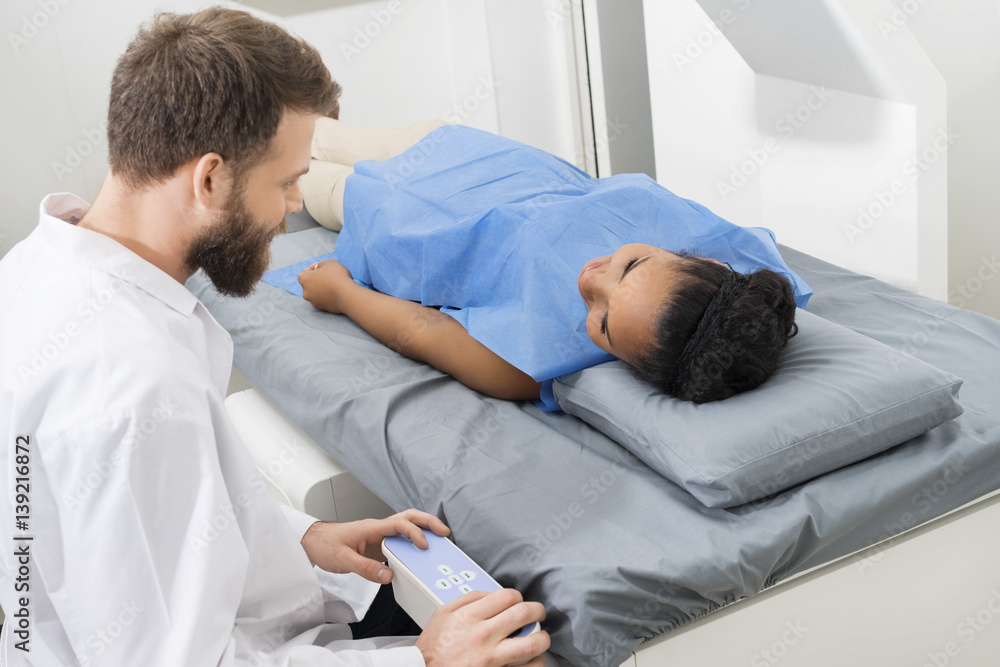 Fototapeta premium Doctor Examining Female Patient Lying On Bed In Hospital