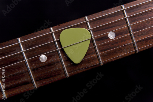 Green guitar pick on the fingerboard