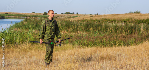 man with a fishing rod in camouflage suit is in the field