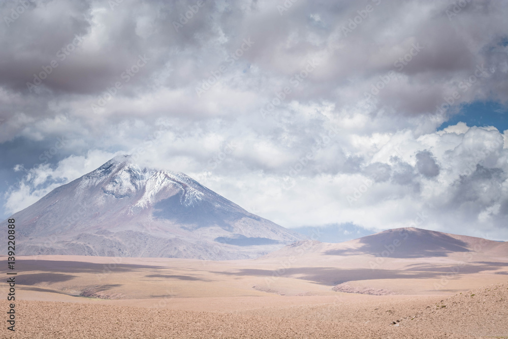 Storm over volcano peaks in the dry desert of the high Andes. Volcanoes in the Andes Mountain range, Chile border with Bolivia, South America.