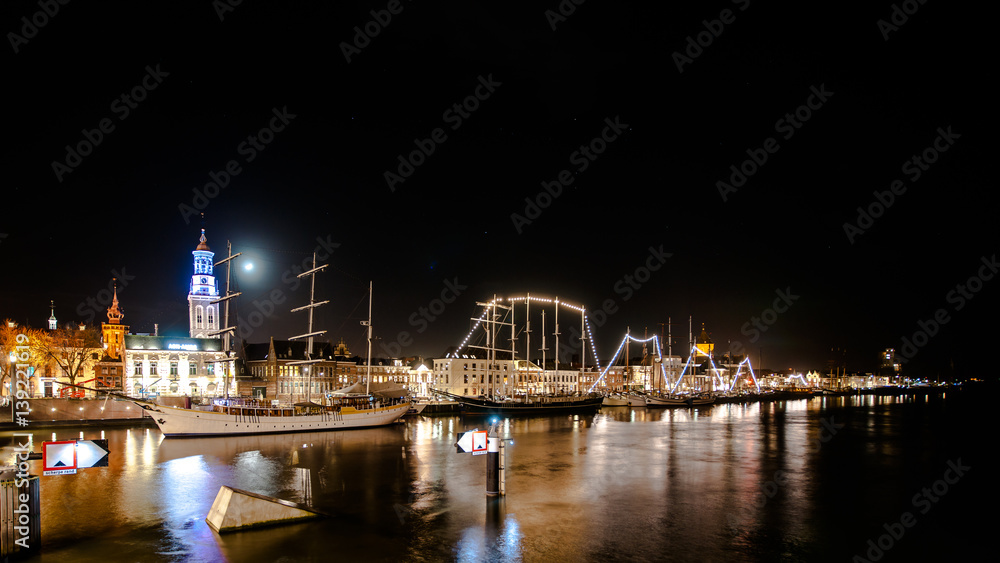 Overlooking the city front and the quay of the city of Kampen at the river IJssel.  Long Exposure photography with just lighted boats along the quay. Overijssel - Netherlands. 