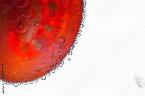 Air bubbles cover red fiber and white grains of red tomato floating in the water photo