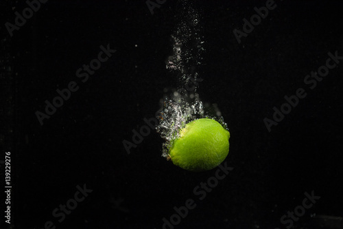 Green lime falls in aquarium with black wall behind it © IVASHstudio