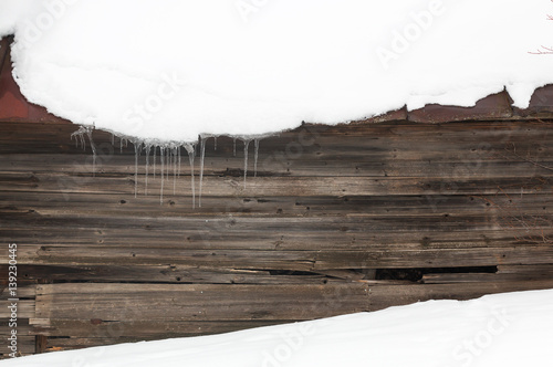 Ice and icicles with snow on a dark wooden background, contrasting winter backdrop