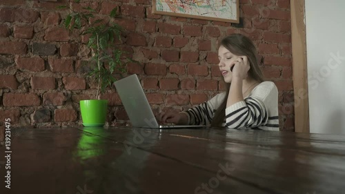 Teenager girl uses laptop while talking on the phone photo