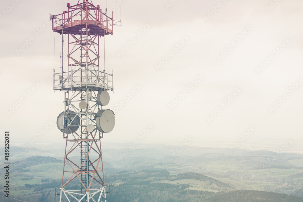 Radio mast over a cloudy valley background