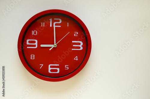 Modern red clock with white background.