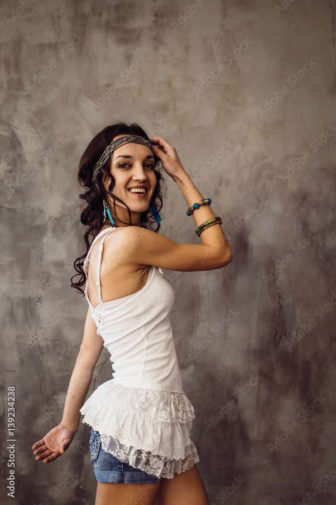 Cheerful girl with curly black hair poses in white t-shirt and jeans shorts Cheerful girl with curly black hair poses in white t-shirt and jeans shorts