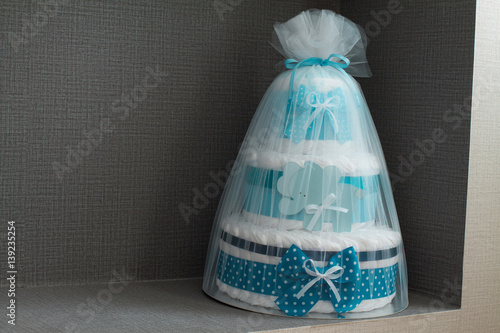 Big cake of diapers with blue bow, baby shower gift.