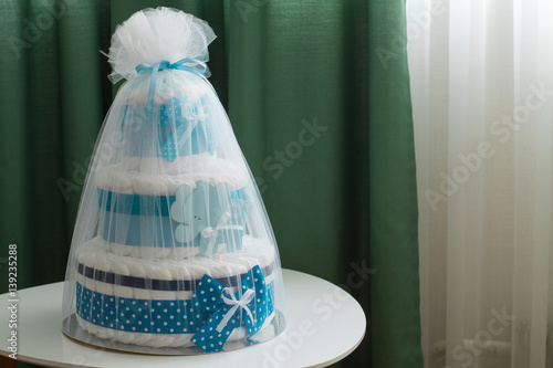 Big cake of diapers with blue bow, baby shower gift.