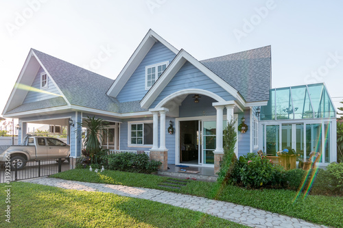 Bright blue house in sunlght with colorful poppies and some graceful trees.