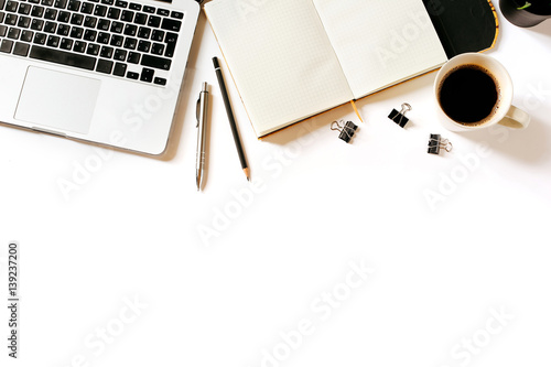 Modern minimalistic work place. White office desk table with laptop, coffee cup, clips, notebook, pen and pencil. Top view with copy space, flat lay