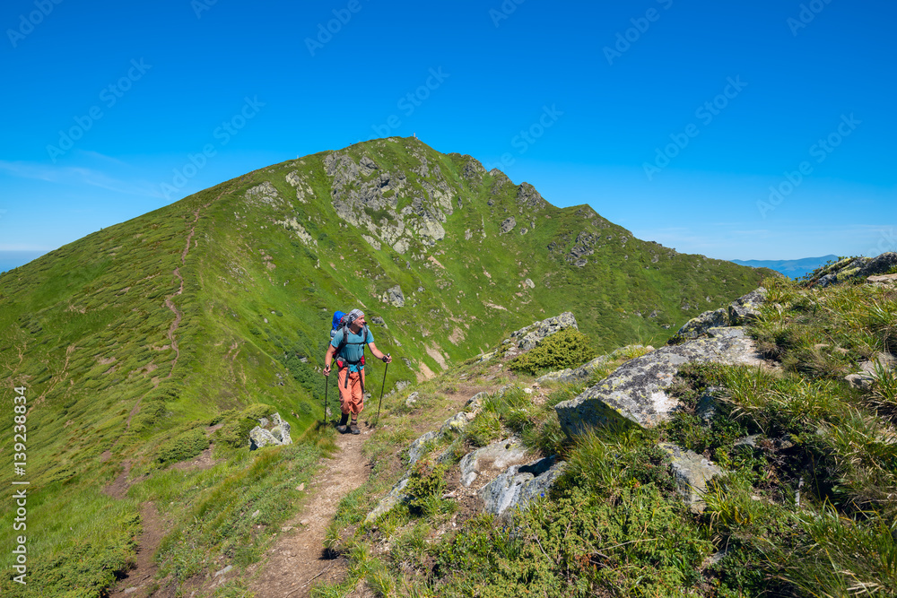 Travelers man with backpack goes along the ridge