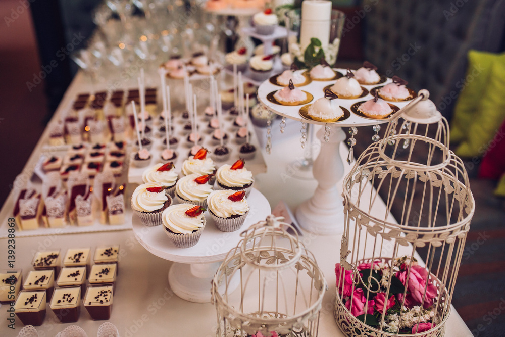 sweet bar with muffins cakes and sweets in area of wedding party