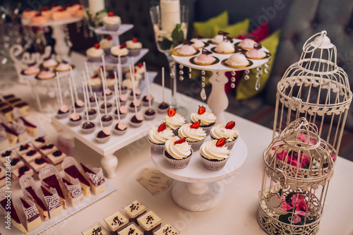 sweet bar with muffins cakes and sweets in area of wedding party © nataliakabliuk
