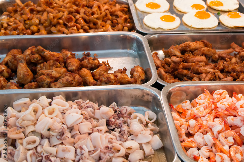 sliced seafood, squid, shrimp and fried chicken on the counter of the Thai market