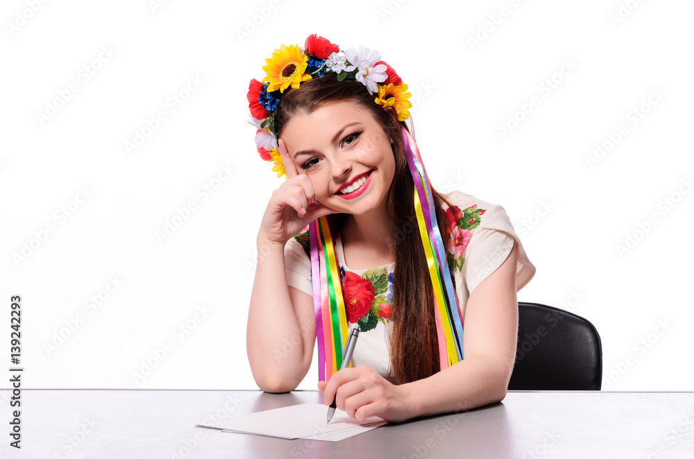 Happy businesswoman with note and pen by a desk.In the Ukrainian national costume Happy businesswoman with note and pen by a desk.In the Ukrainian national costume