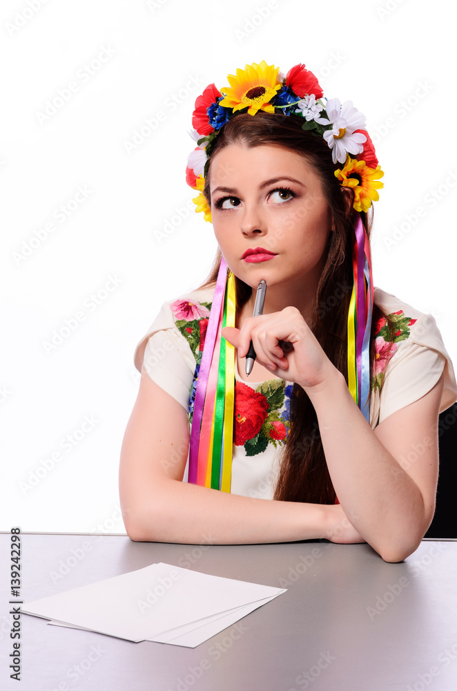 Happy businesswoman with note and pen by a desk.In the Ukrainian national costume Happy businesswoman with note and pen by a desk.In the Ukrainian national costume