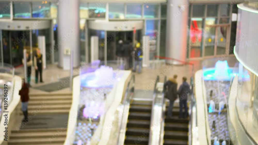 Shopping Center. People on escalators rise to an exit from shopping center and go down in it Shopping Center. People on escalators rise to an exit from shopping center and go down in it