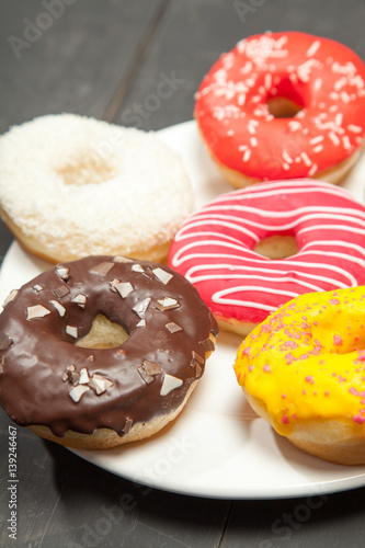 Colorful donuts on a black wooden background
