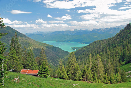 Beautiful panorama of Walchensee in the bavarian alps with a red hut in the front