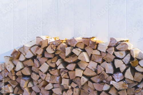 Foto plenty of firewood stacked next to the wall.